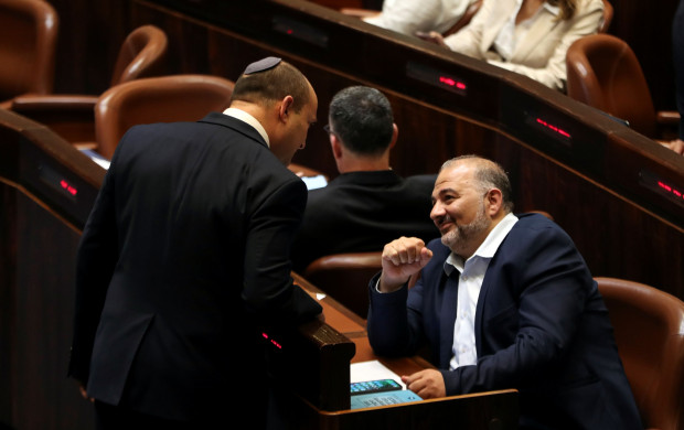 <p>Naftali Bennett, Prime Minister-designate chats with United Arab List party leader Mansour Abbas during a special session of the Knesset, Israel's parliament, whereby a confidence vote will be held to approve and swear-in a new coalition government, in Jerusalem June 13, 2021. REUTERS/Ronen Zvulun</p>
