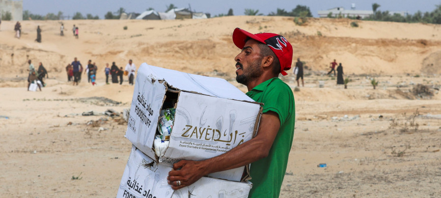 <p>A Palestinian man carries food items collected from aid packages dropped from an airplane, amid a hunger crisis, in Deir Al-Balah, in the central Gaza Strip, August 12, 2025. REUTERS/Ramadan Abed</p>