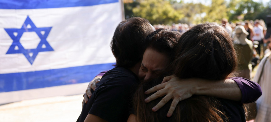 <p>People hug in front of Israeli flag, as friends and family mourn Vivian Silver, 74, a Canadian-born peace activist from Kibbutz Beeri who was killed in the deadly October 7 attack by Palestinian Islamist group Hamas from the Gaza Strip, at a memorial service, at Kibbutz Gezer, Israel November 16, 2023. REUTERS/Ronen Zvulun</p>