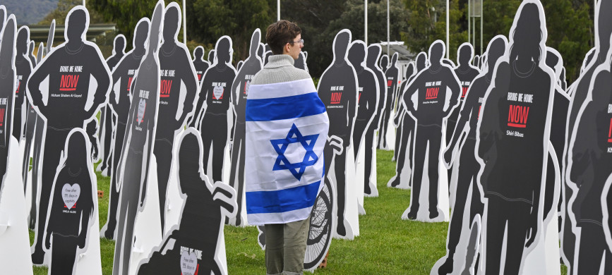 <p>A supporter of Israel walks amongst cutout cardboard effigies, representing Israeli hostages, during a protest outside Parliament House in Canberra, Australia, Tuesday, Nov. 28, 2023. Relatives and a friend of Israelis kidnapped and killed by Hamas visited Australia's Parliament House on Tuesday, sharing personal stories to lobby for international support for all hostages to be freed and to support Israel's war effort.(Mick Tsikas/AAP Image via AP)</p>